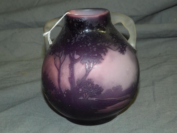 Small dark purple cameo-style glass vase with a raised tree and landscape scene in lighter color on the front.