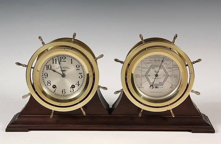 SHIP'S CLOCK & BAROMETER DESK SET - Circa 1920s Seth Thomas Seven Jeweled Eight-Day Ship's Bell Clock along with Taylor Stormoguide Barometer, dated 1922, in matching brass ships wheel cases, set in mahogany cradle, w. sold by Thomaston Place Auction Galleries, lot 734 — auction record photograph