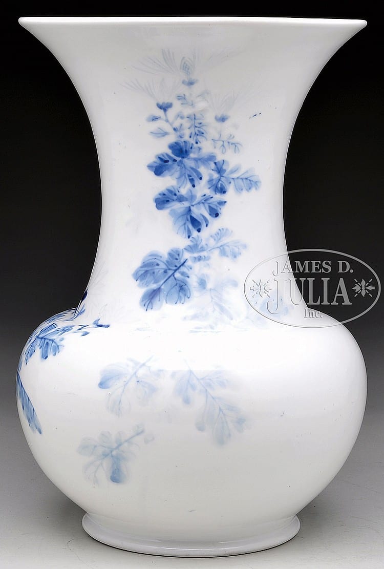 White porcelain vase with blue floral and branch decoration, rounded body and flared trumpet-shaped neck against a dark background.