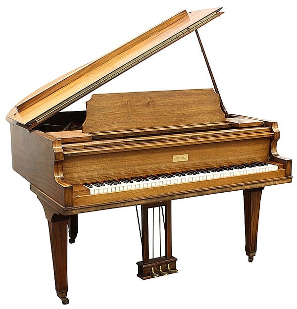Wooden baby grand piano with its lid open, showing the keyboard and strings inside.