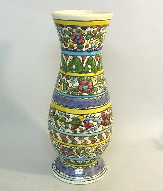 Tall ceramic vase with green and multicolor floral pattern bands and blue stripe trim, shown against a light background.