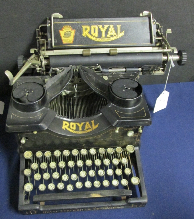Vintage black typewriter with “ROYAL” branding on the front and top plate, shown from above on a blue background.