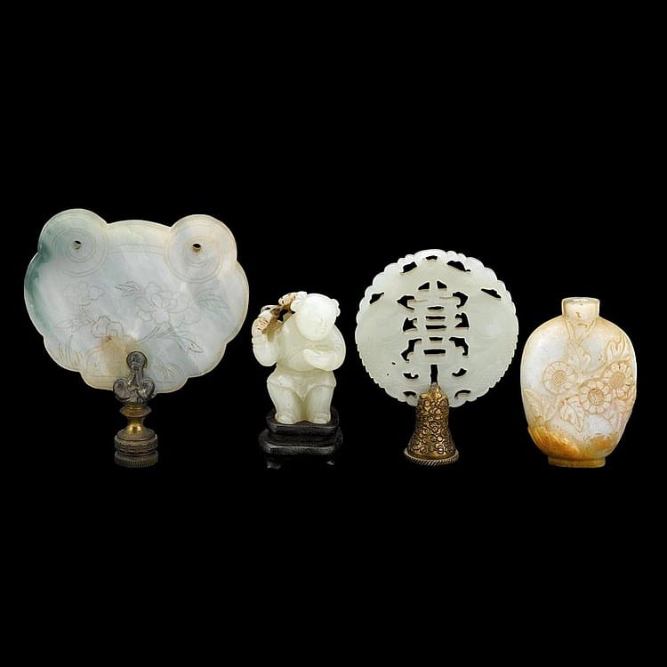 Four small pale carvings on a dark background: a jade-like round plaque, a standing figure, a circular disc with Chinese character-like cutouts, and a vase.