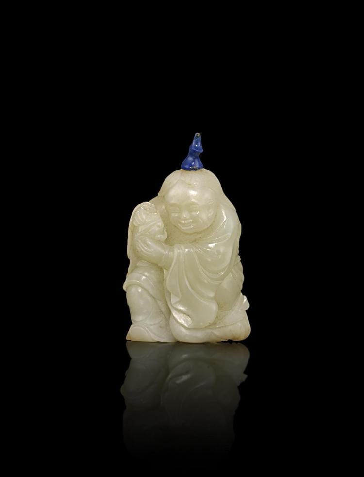 Carved pale stone snuff bottle shaped like a seated laughing figure, with a small blue cap, shown against a black background.