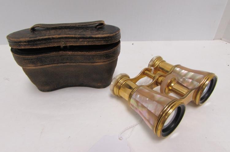 Brass opera glasses with mother-of-pearl style barrels and black eyepiece ends, shown next to a brown leather case.