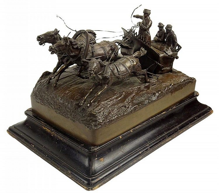 Bronze horse-and-rider sculpture with three horses and a mounted figure on a dark wood base.