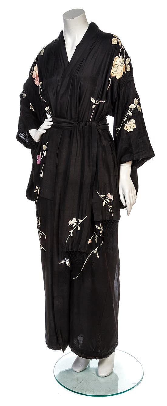Black robe or kimono with wide sleeves, floral embroidery in white and pink, and a tied belt, shown on a mannequin.