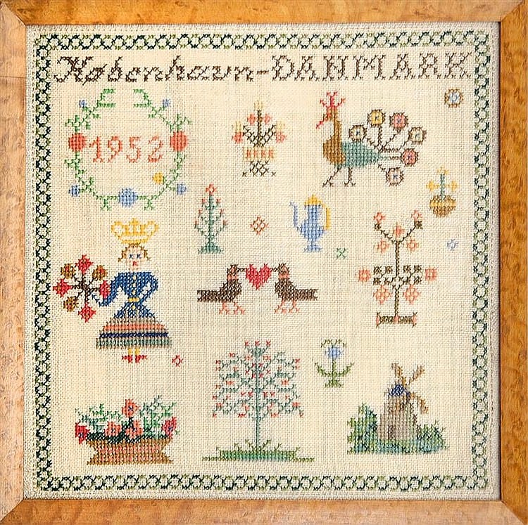 Framed needlepoint sampler with a cream background and colorful stitched floral and geometric motifs arranged in rows.