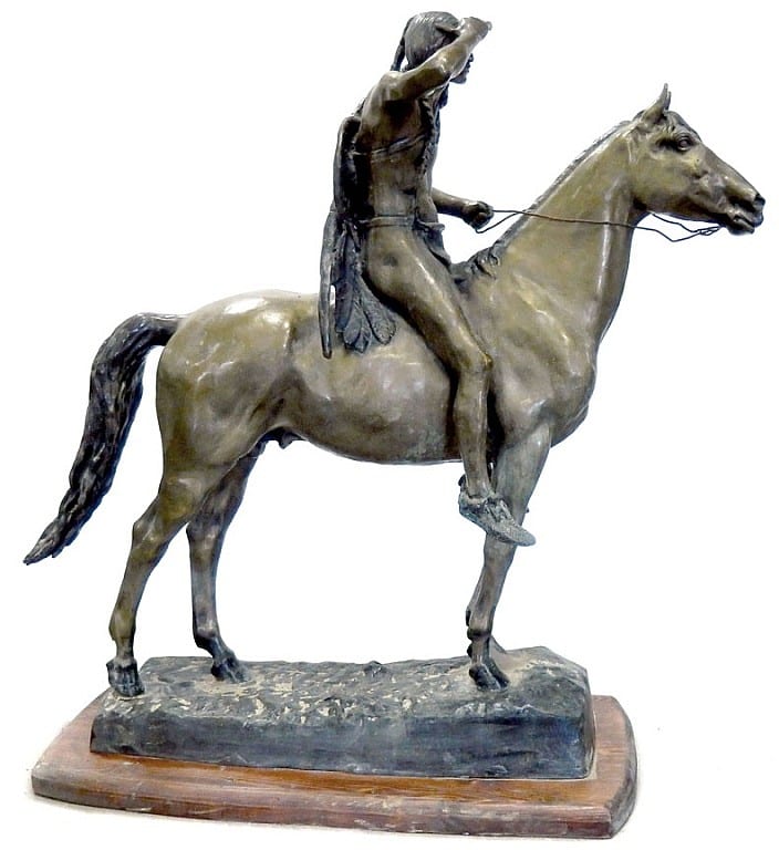 Bronze sculpture of a rider holding the reins while seated on a galloping horse, shown on a rectangular base.
