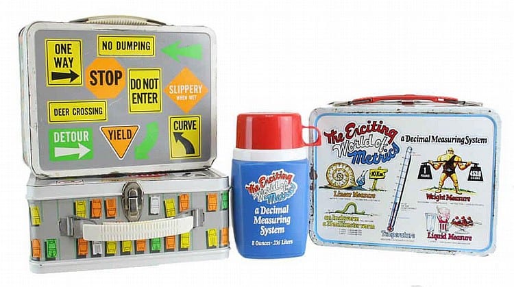 Three vintage-style lunch boxes and a matching thermos canister with road-sign graphic panels and the text “The Accting World of the Met…”