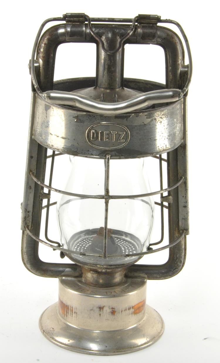 Vintage Dietz firemans lantern with metal handle, glass reservoir, and protective wire cage.