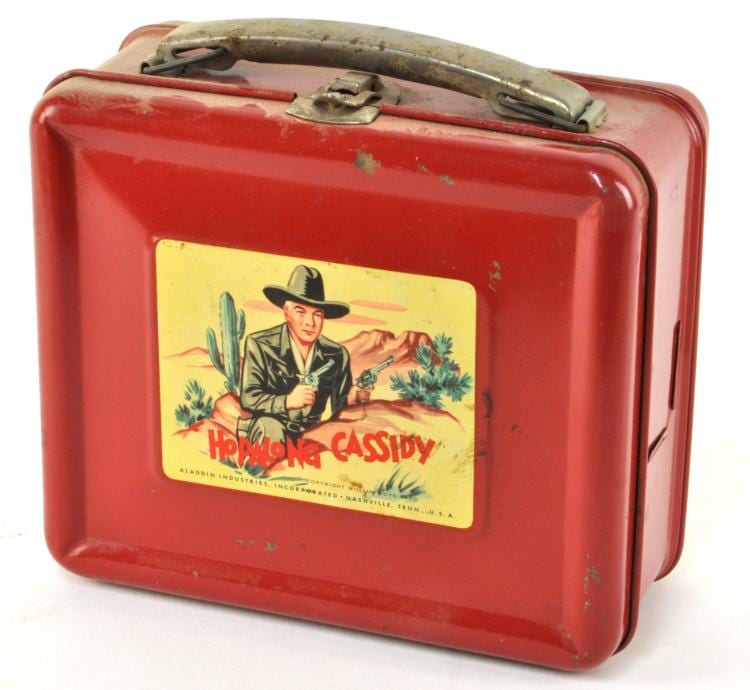 Red vintage lunch box with a illustrated Hopalong Cassidy cowboy graphic on the front and metal clasps on the lid.