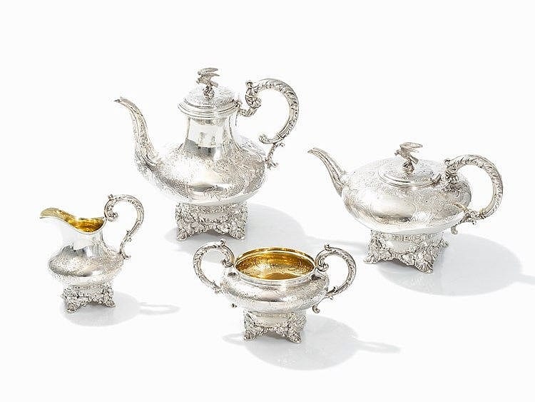 Set of silver coffee and tea service: teapots and a small creamer with a sugar bowl, gold interior shown, on a white background.