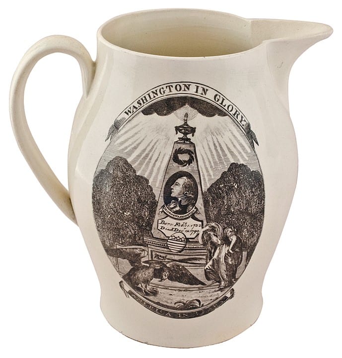 White ceramic creamware-style pitcher with a black printed emblem and figures, shown front view.