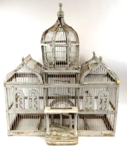 White-painted Victorian-style birdcage with arched panels, three open sections, and a finial top on a light background.