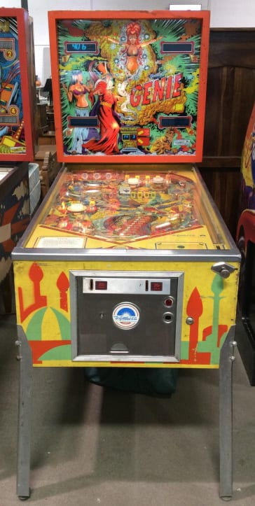 Vintage pinball machine showing a Genie themed backglass with colorful characters and score lights, with flippers and playfield visible.