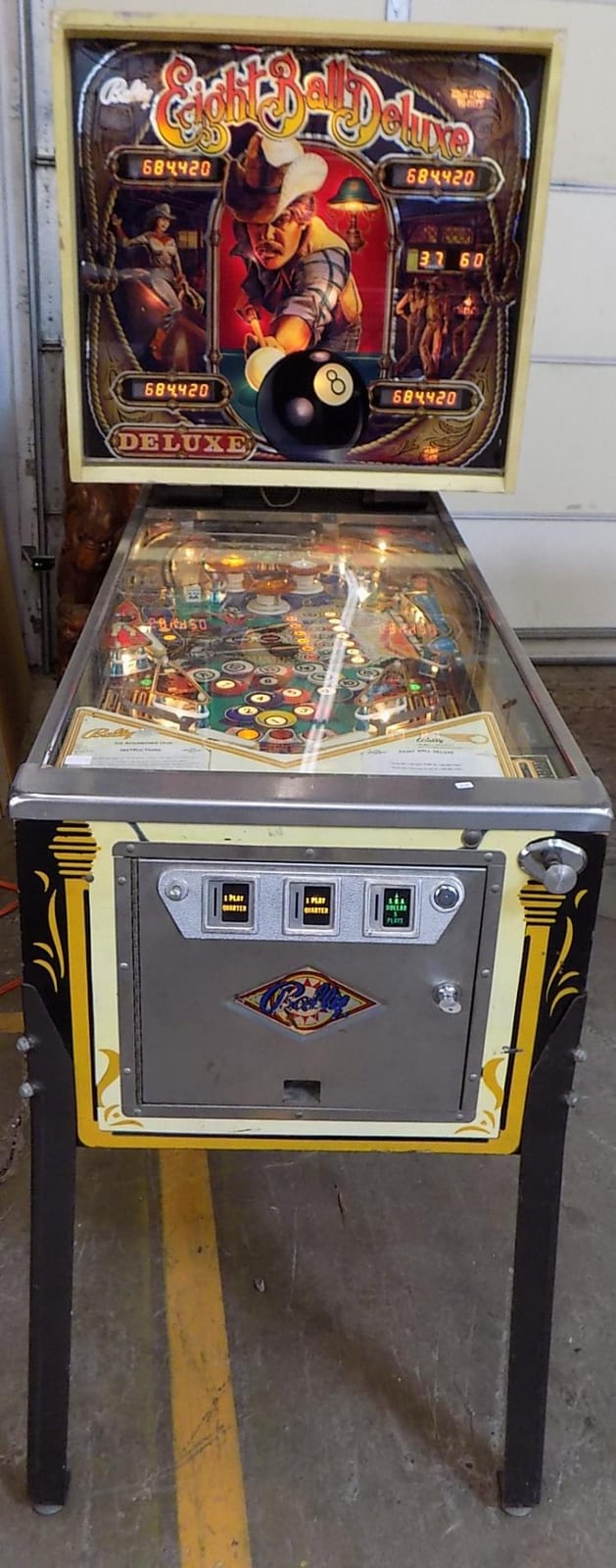 Rear view of a Bally 8-Ball Deluxe pinball machine with illuminated backglass and playfield controls.