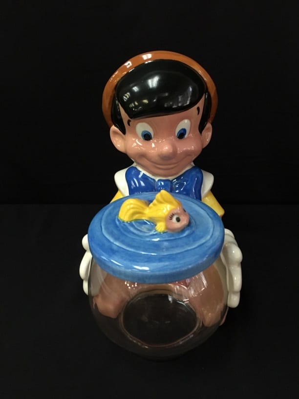 Ceramic cookie jar shaped like a cartoon boy with blue outfit and a blue bowl, holding a small gold fish on top.