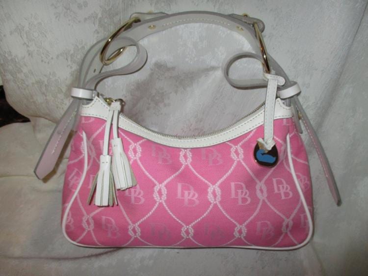 Pink and white Dooney & Bourke handbag purse with a curved top handle, white trim, and a tassel charm