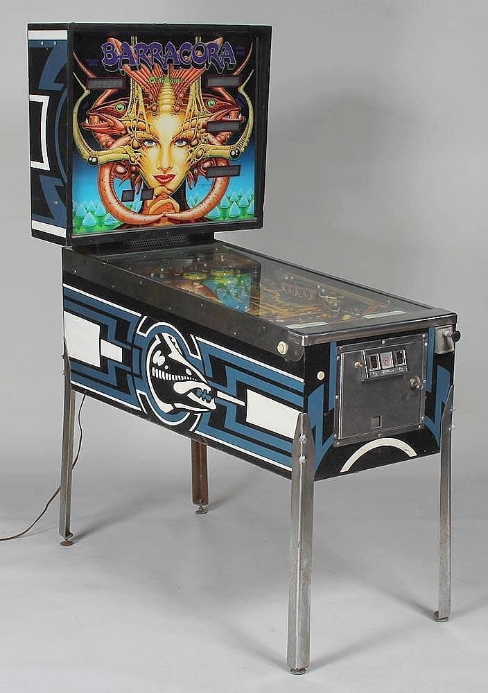 Retro pinball machine with blue-and-black artwork and a screen showing the title “Barracora,” with the playfield open on top.