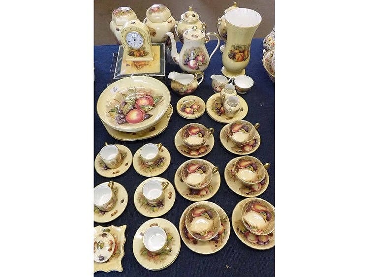 Assorted vintage floral china dishware set on a blue cloth, including cups, saucers, small bowls, and teapot and creamer forms with gold trim.