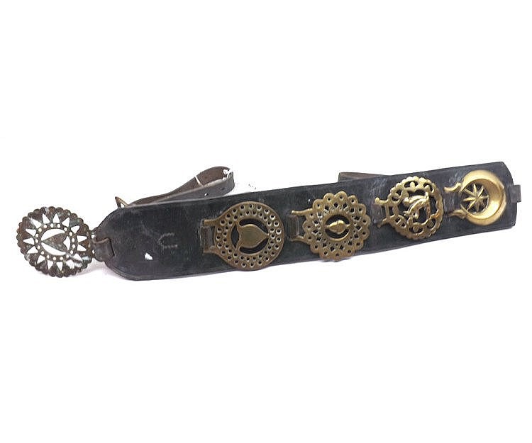 Vintage dark leather horse harness strap with metal decorative medallions and rings, shown on a white background.