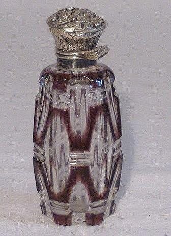 Small cut-glass perfume bottle with purple-tinted sides and a silver-toned ornate cap.