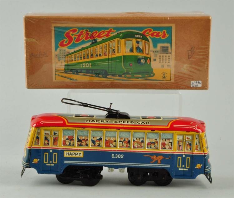 A colorful tin toy trolley bus with wheels and windows, shown with its cardboard box behind it.