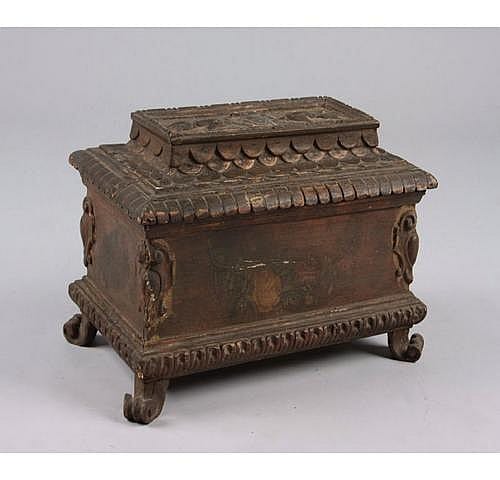 Closed decorative jewelry box with ornate carved borders, small feet, and arched panel sides, photographed on a light background.