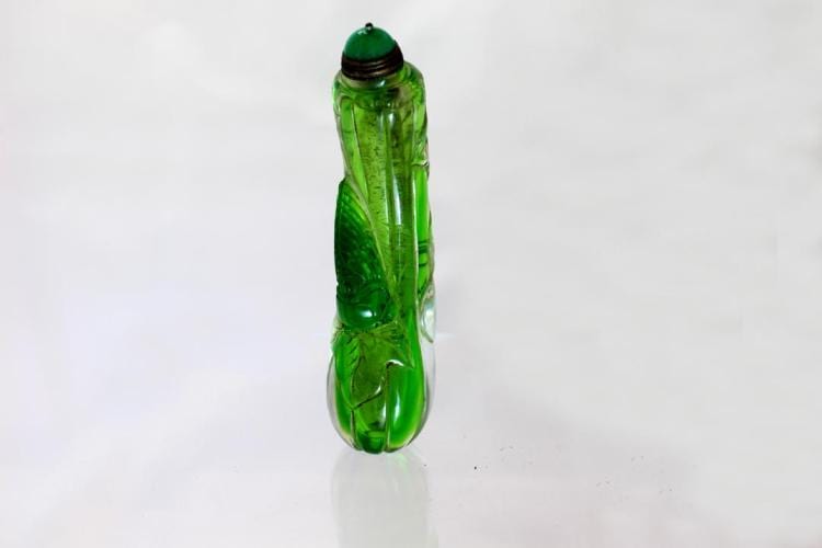 Small green snuff bottle with a rounded body and dark green cap, photographed against a white background.