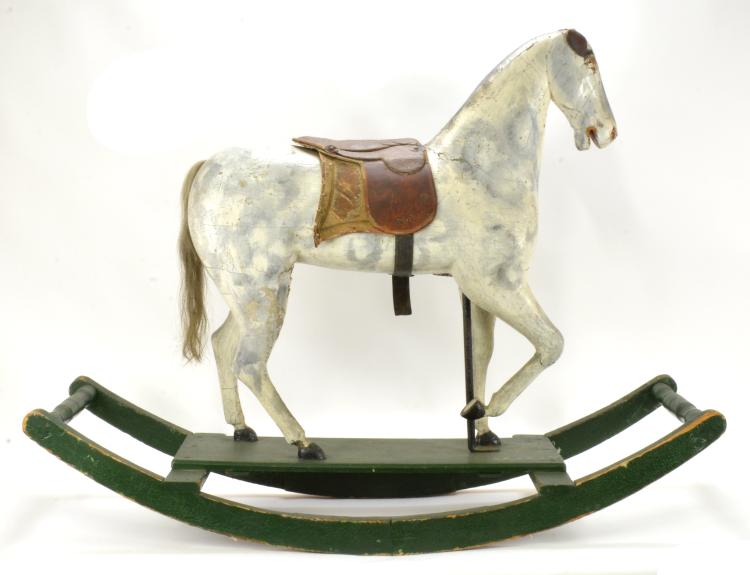 White wooden rocking horse with a brown saddle and green curved rocker base.