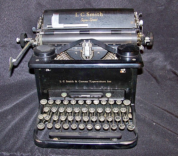 Vintage L.C. Smith typewriter on a dark cloth background with visible keys and paper feed roller.