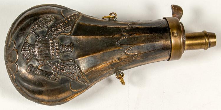 Metal black powder flask with a circular base, engraved crest, and brass nozzle with spout opening.