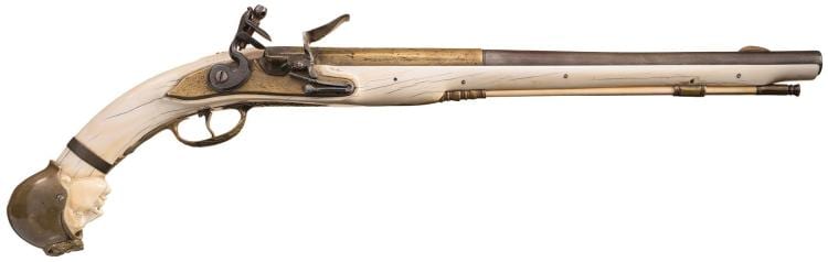 Side view of a flintlock-style pistol with a wooden stock, metal barrel, and curved trigger guard on a white background.