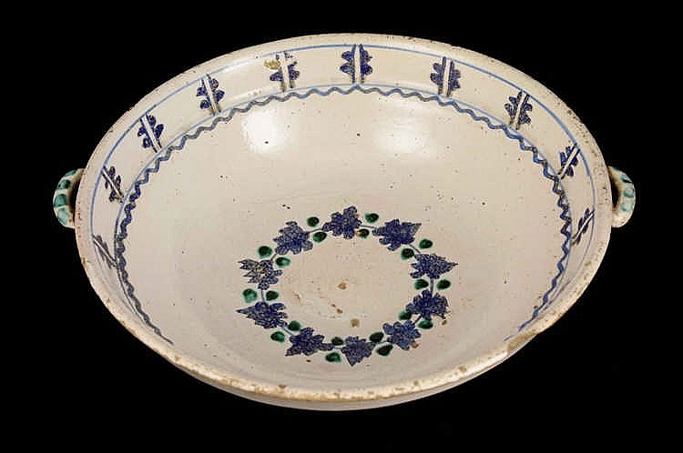 White ceramic bowl with blue and green floral wreath decoration and small blue cross-like motifs around the rim.