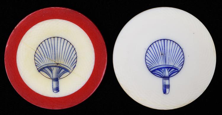 Two circular poker chips with blue scrimshaw-style fan-and-column designs, one red-and-cream and one white-and-cream, photographed side by side.