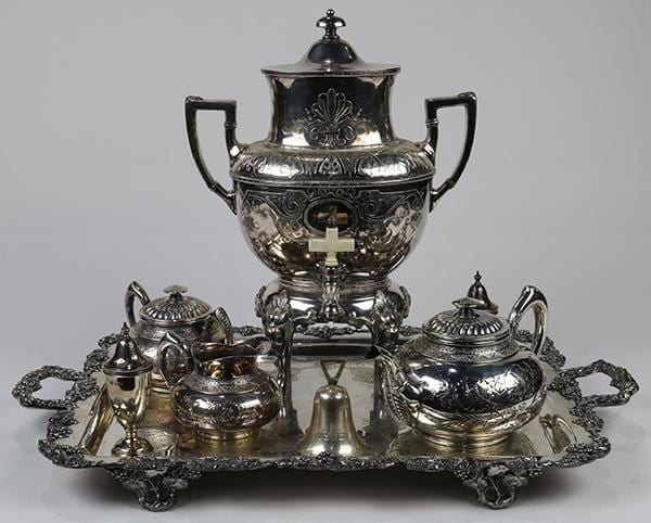 Silver-toned Victorian-style tea service set on a tray with a lidded urn, covered sugar and teapot, and creamer.