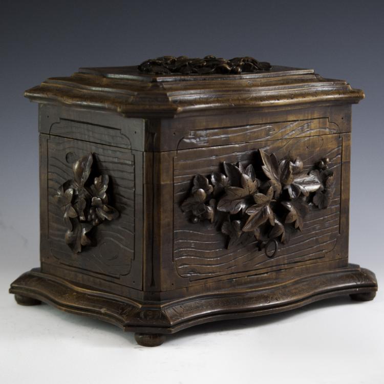 Carved wooden cigar box with ornate floral panels on the sides and a carved lid with raised detailing.
