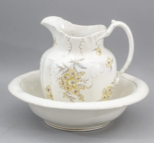 Porcelain wash basin with a matching pitcher, both with white glaze and yellow floral decoration.