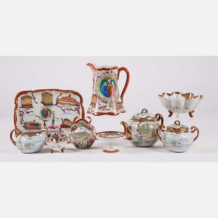 Collection of vintage porcelain tea service pieces on a white background, including a pitcher, creamers, sugar bowl, bowl, and tray with colorful scenic designs