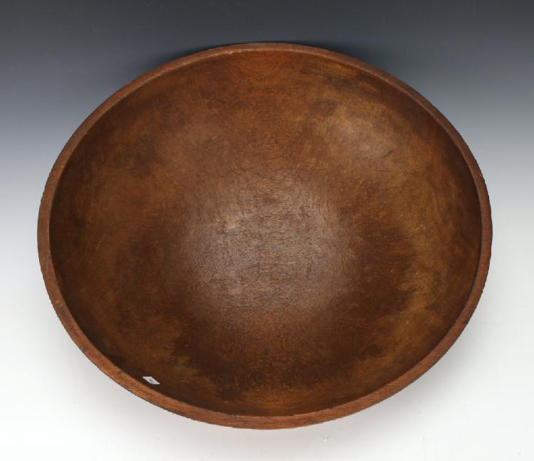 Top view of a large round wooden bowl with a worn, natural brown surface.