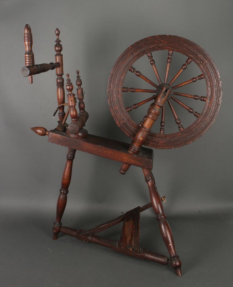 Antique wooden spinning wheel with a large circular wheel, upright posts, and a spindle for drafting and winding fiber.