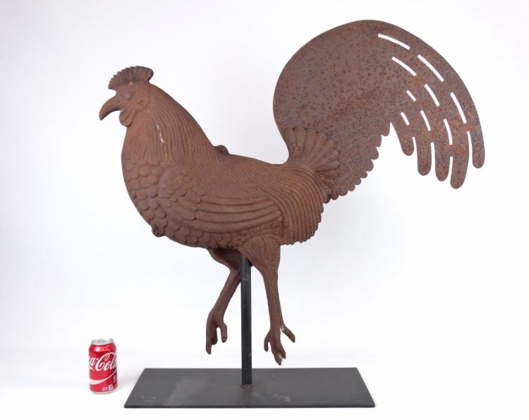 Rusty metal rooster weathervane with outstretched tail and wings mounted on a base against a plain white background.