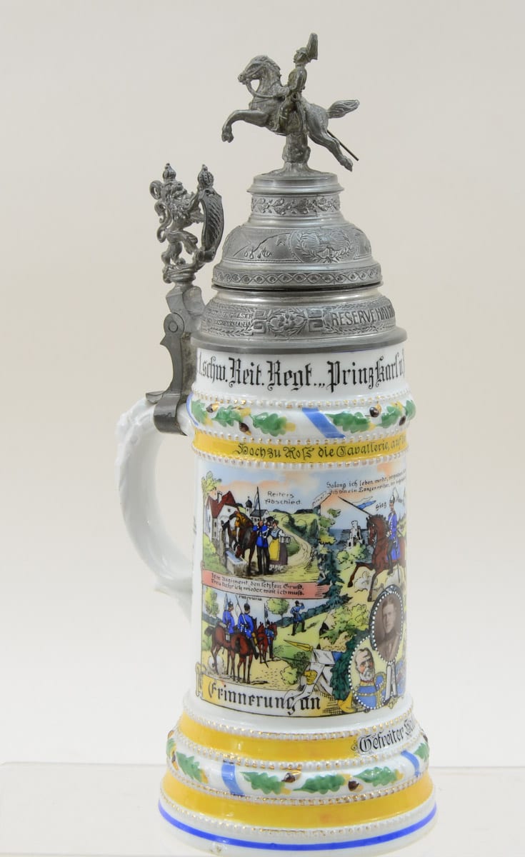 German beer stein with pewter lid and knight finial, decorated with painted scenes and gold and blue trim.