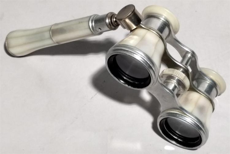 Antique-style brass opera glasses with binocular eyepieces and ivory-colored handgrips on a white background.