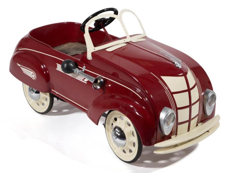 Red pressed-steel pedal car with cream fenders, round headlights, and a steering wheel on a white background.