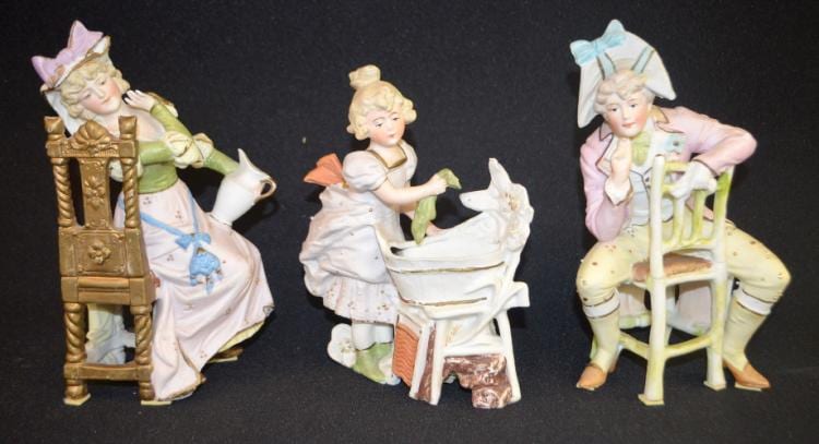 3 Antique Bisque Figurines: 1.) #9784, Lady holding a pitcher and seated in an ornate chair.; 2.) #8805, Man seated backwards on a kitchen chair.; 3.) Unmarked, a lady doing laundry in a tub with a washboard at her feet. sold by Tom Harris Auctions, lot 94 — auction record photograph