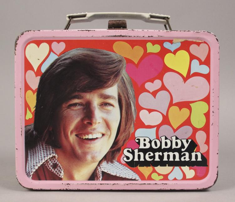 Vintage metal lunch box with a smiling portrait and colorful heart pattern, labeled “Bobby Sherman.”