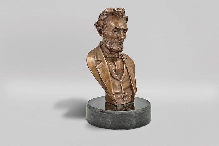 John Rogers, New York, a small bronze bust of Abraham Lincoln, the pose very much like that seen in a contemporary photograph by Matthew Brady, the president seemingly deep in thought, the well modeled figure mounted to a round, black granite base sold by Schmitt Horan & Co., lot 601 — auction record photograph