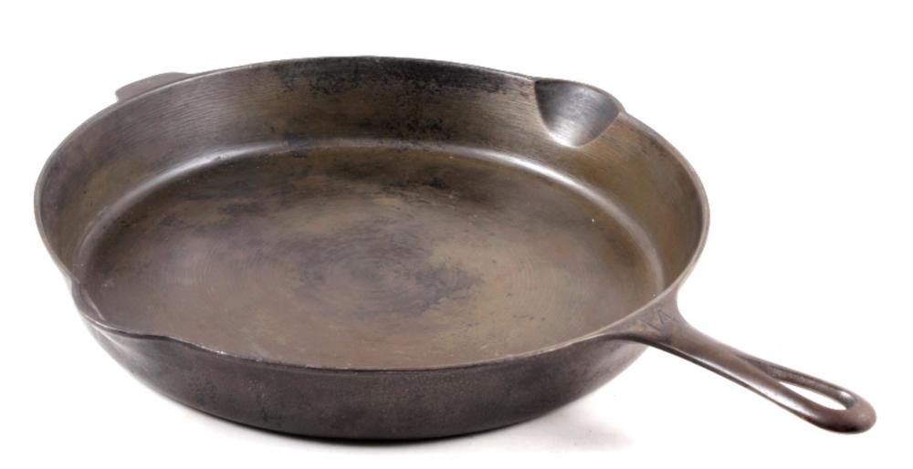 Metal cast iron skillet with a rounded shallow pan and short handle, shown from the side on a white background.